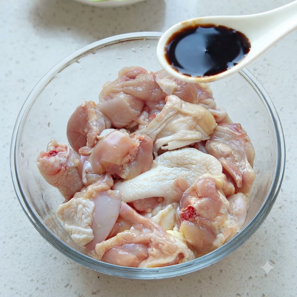 一勺深色酱油正被加入装有生鸡肉块的玻璃碗中。