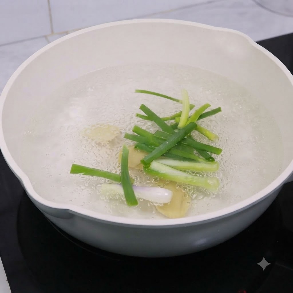 調理酒を入れたお湯の入った鍋の中で、生姜のスライスと青ネギが茹でられている様子。