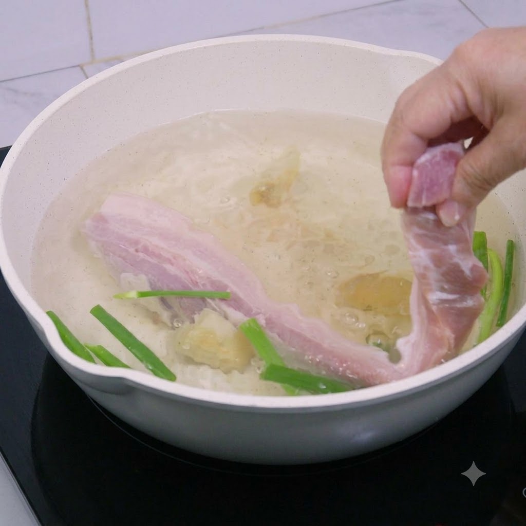 豚バラ肉の細切りが沸騰したお湯の鍋に下ろされている様子。