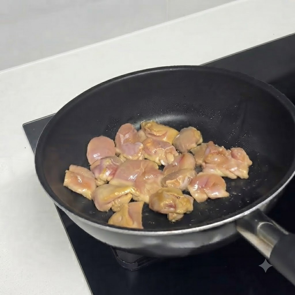 油をひいた熱々のフライパンで鶏肉のピースがジューシーに炒められている様子。