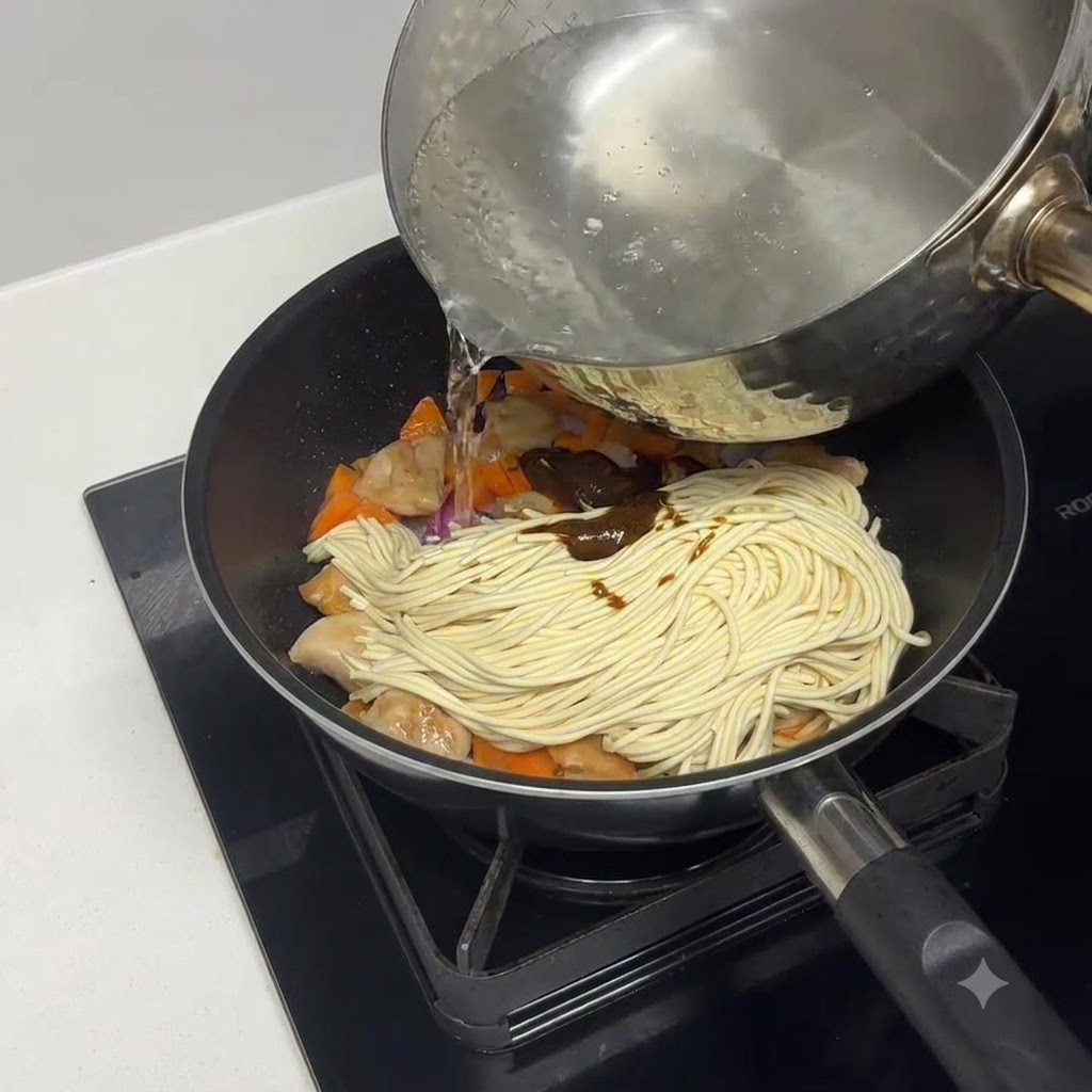 パスタや具材の入ったフライパンにお湯が注がれている様子。