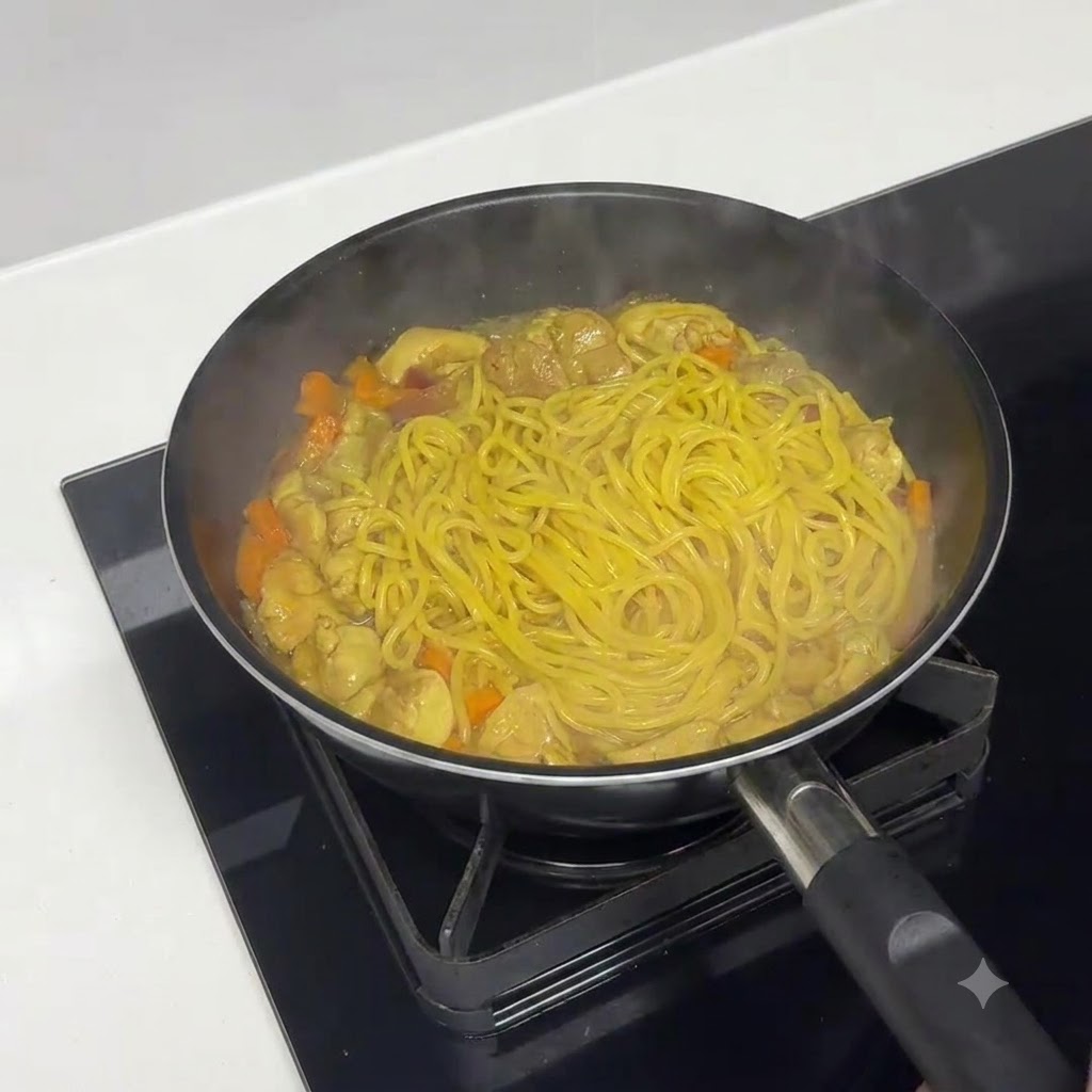 中火で水分を飛ばしながらソースを煮詰め、パスタを調理している様子。