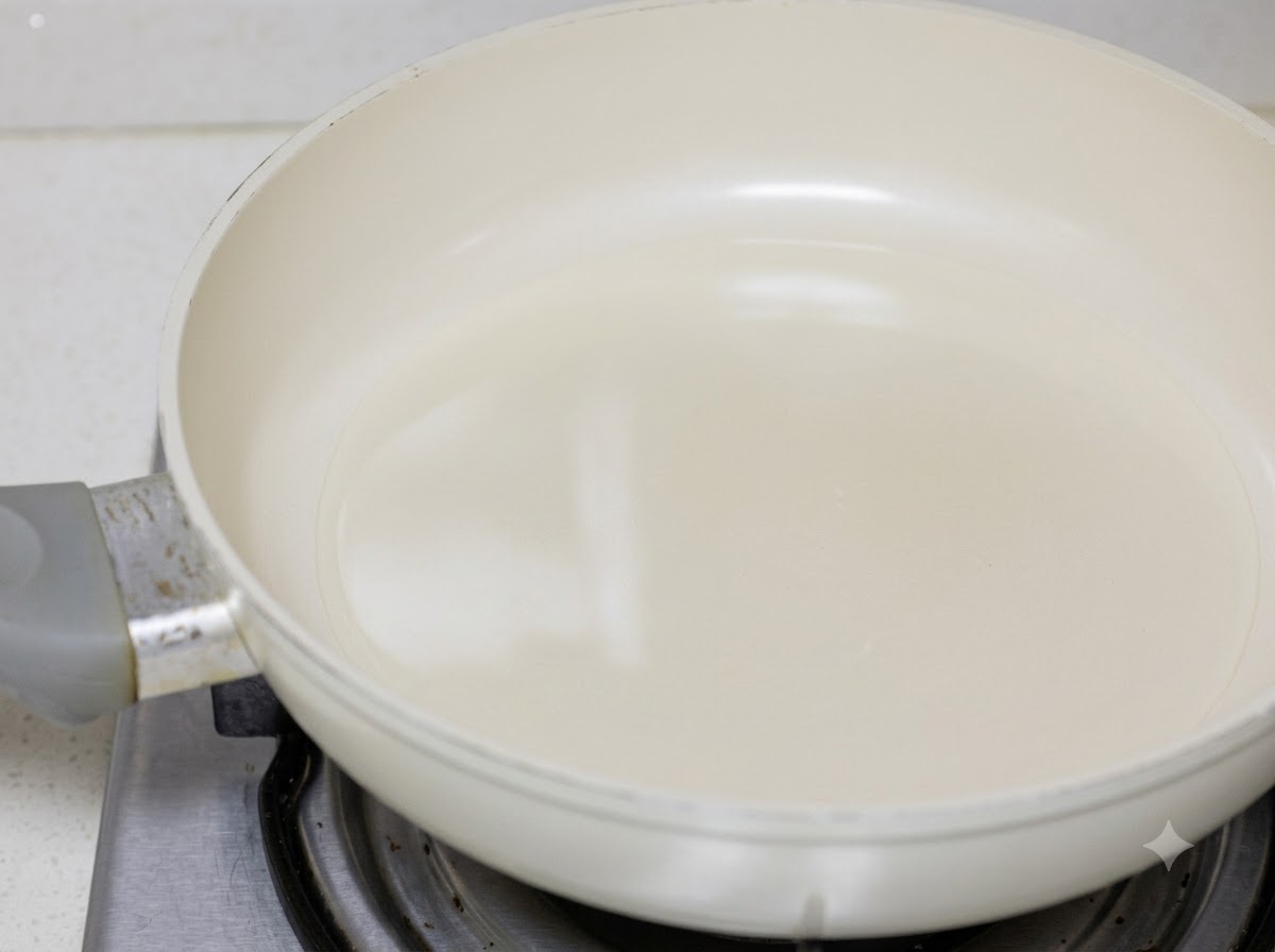白いフライパンの中で調理油を使って炒められている鶏肉。