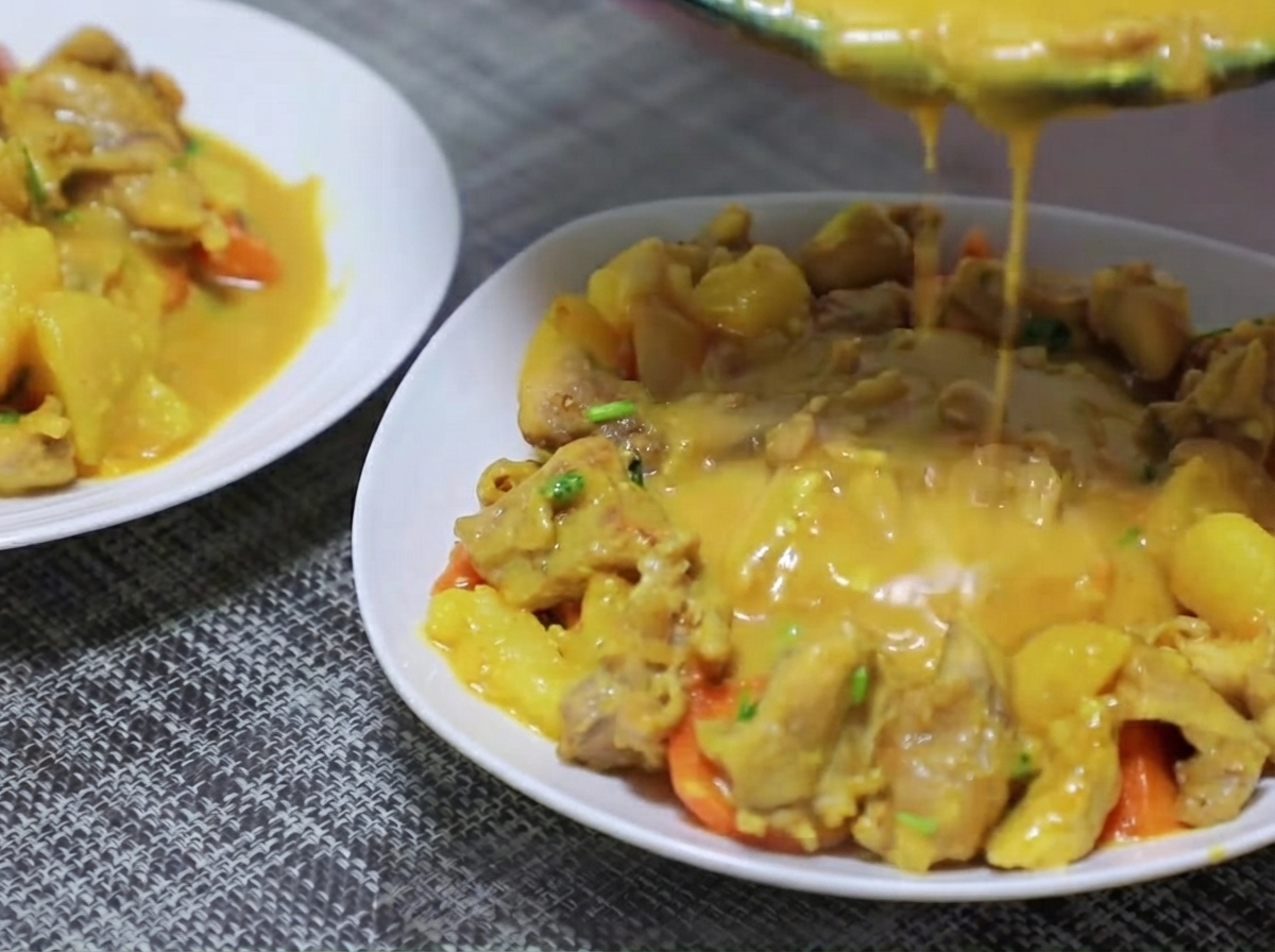 カレーのベースと一緒にフライパンで炒められている乱切りのジャガイモとニンジン。