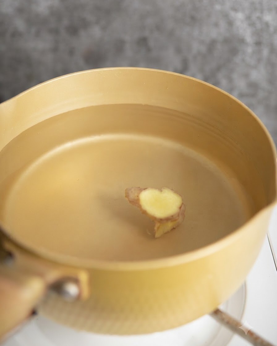 生姜スライスを入れたお湯で鶏肉を下茹でしている様子。