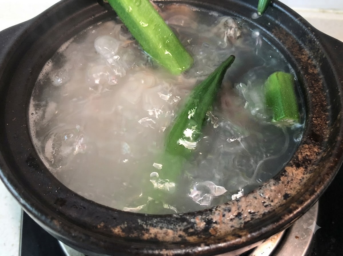 ぐつぐつと煮える豚骨スープの中に、丸ごとの緑のオクラを入れているところ。