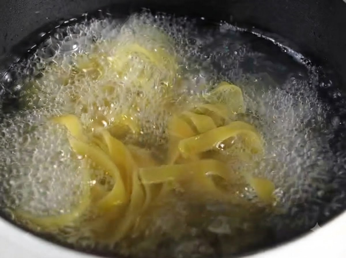 丸いグレーの皿に、茹で上がったフェットチーネが綺麗に盛られているクローズアップ。
