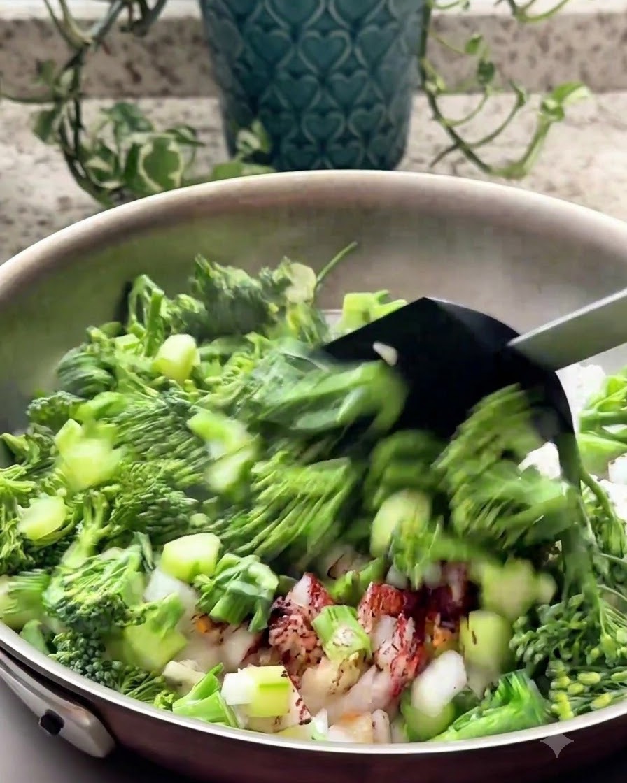 黒いスパチュラを使って、フライパンで刻んだブロッコリーと香味野菜を炒めている様子。