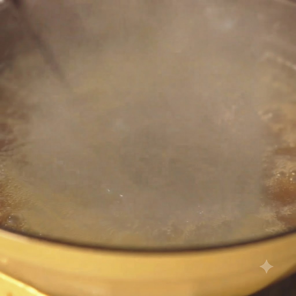 黄色い鍋の中で湯気が立ち上りながら、スパゲッティが勢いよく茹でられている様子