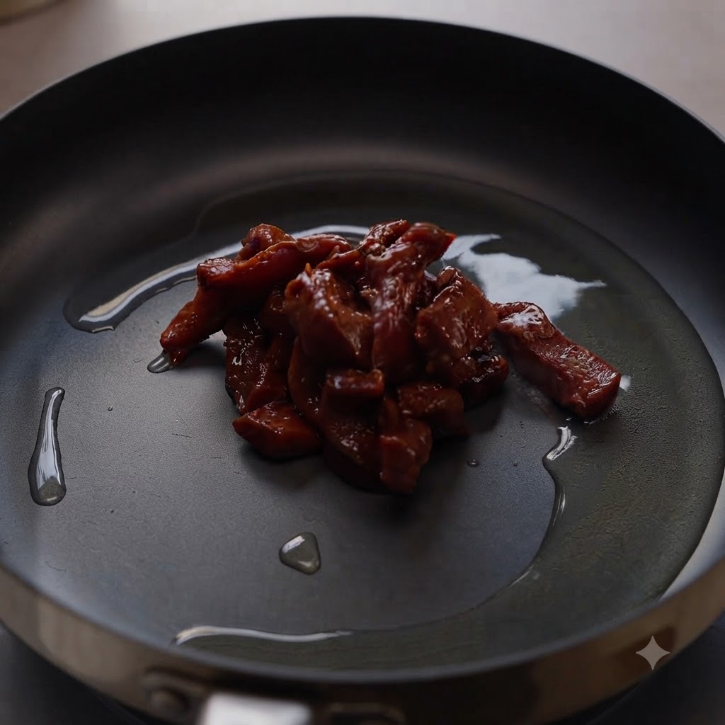 油を引いた熱いフライパンの中央で香ばしく焼ける味付け牛肉。