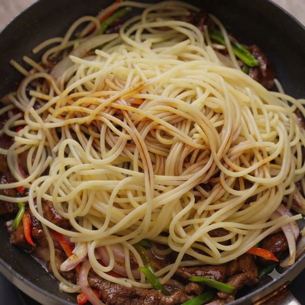 フライパン内のスパゲッティと牛肉にタレが回しかけられる様子。