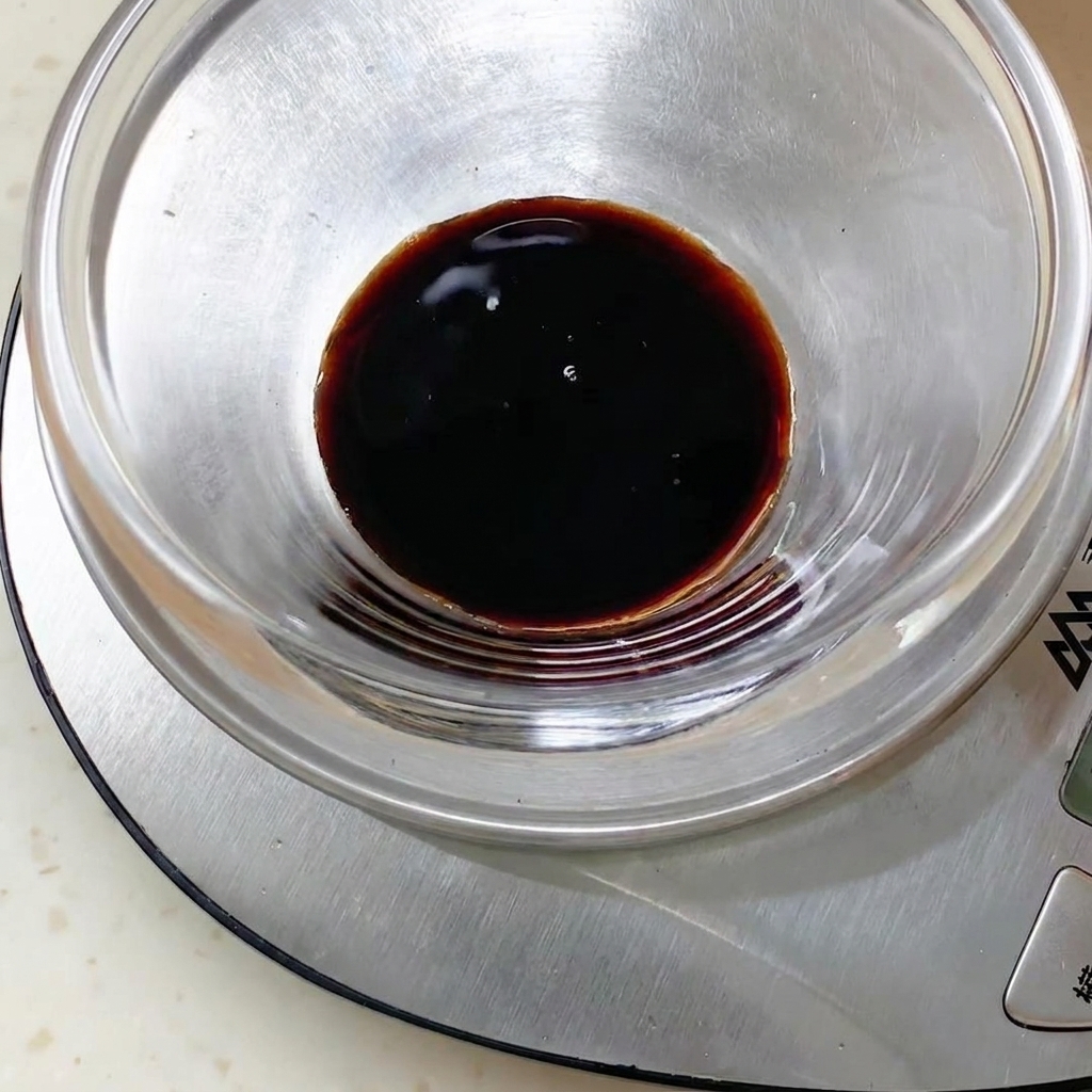 デジタルスケールの上に置かれたガラスボウルの中の黒いソース液。