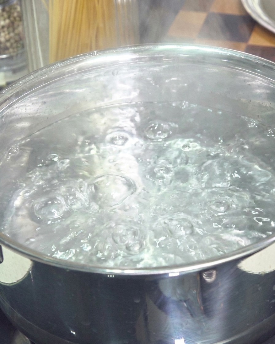 表面に泡が立ち、勢いよくお湯が沸騰しているステンレス製の鍋。