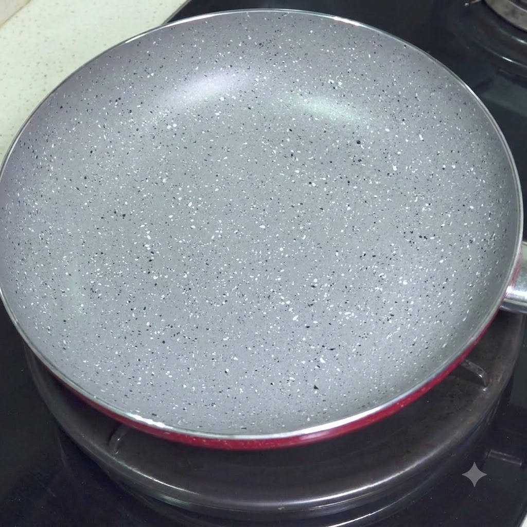 コンロの火にかけられた、グレーの斑点模様の空のノンスティックフライパン。