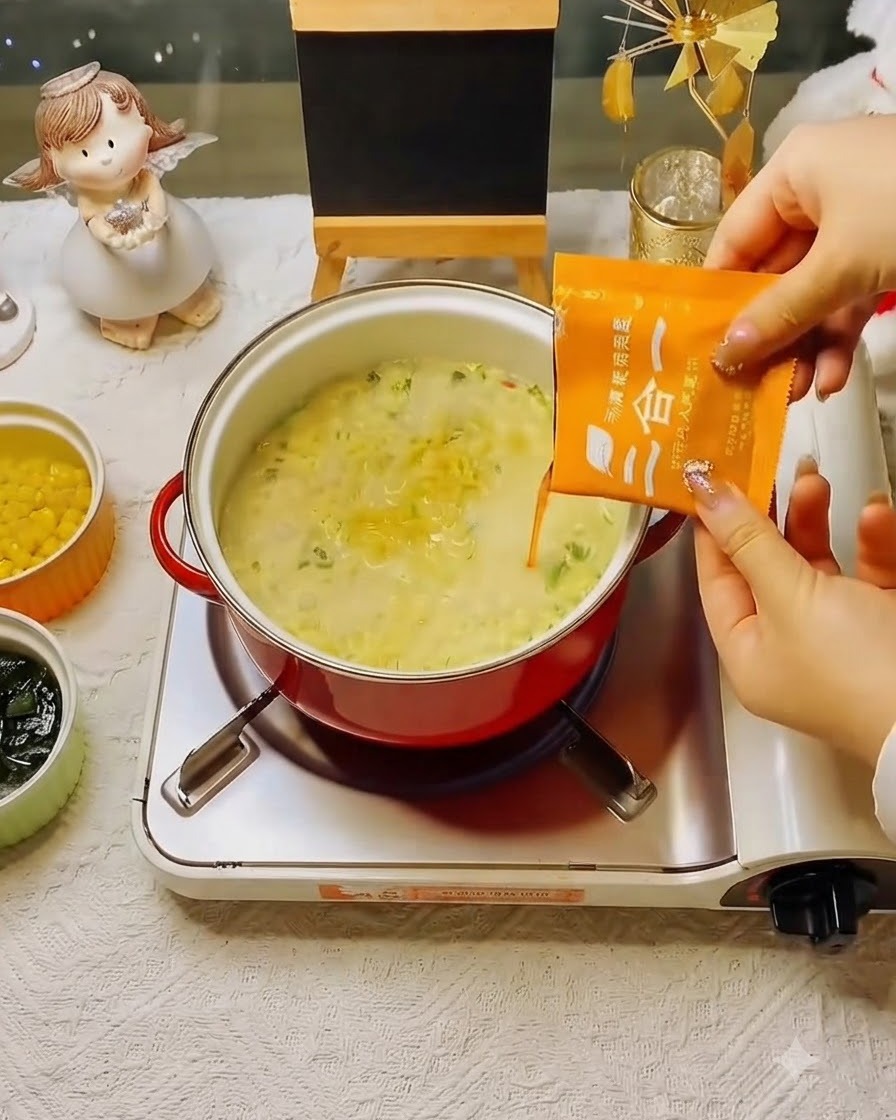 オレンジ色の粉末スープを、鍋で煮立っている麺に加えている様子。
