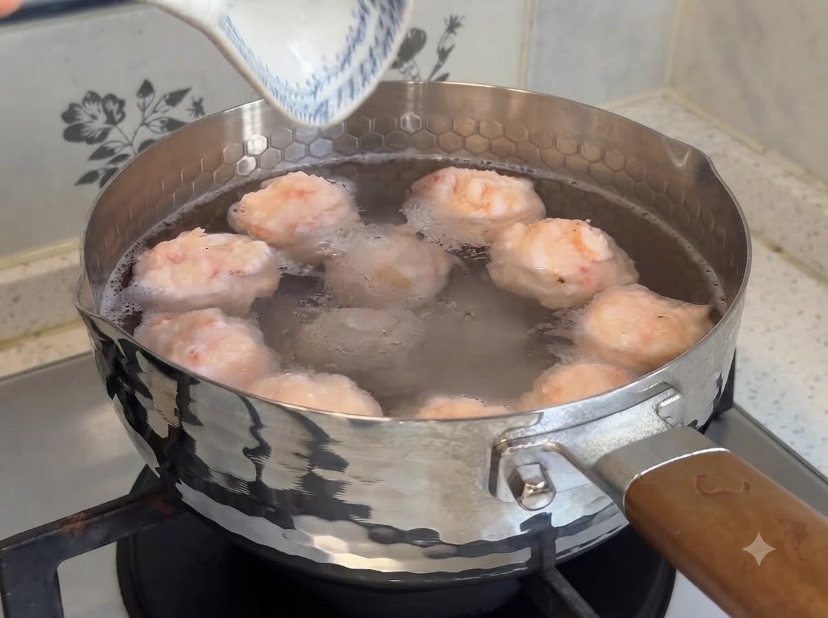 コンロの上の温かいお湯が入った鍋で、ぷりぷりの手作り海老団子が茹でられている様子。