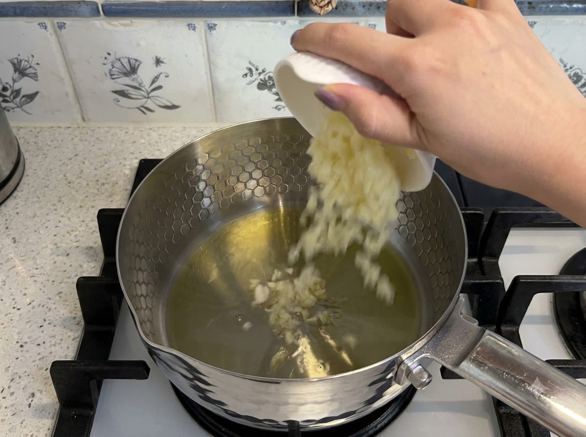 鍋の熱した油に、みじん切りにされたにんにくと角切りのトマトが加えられて炒められている様子。