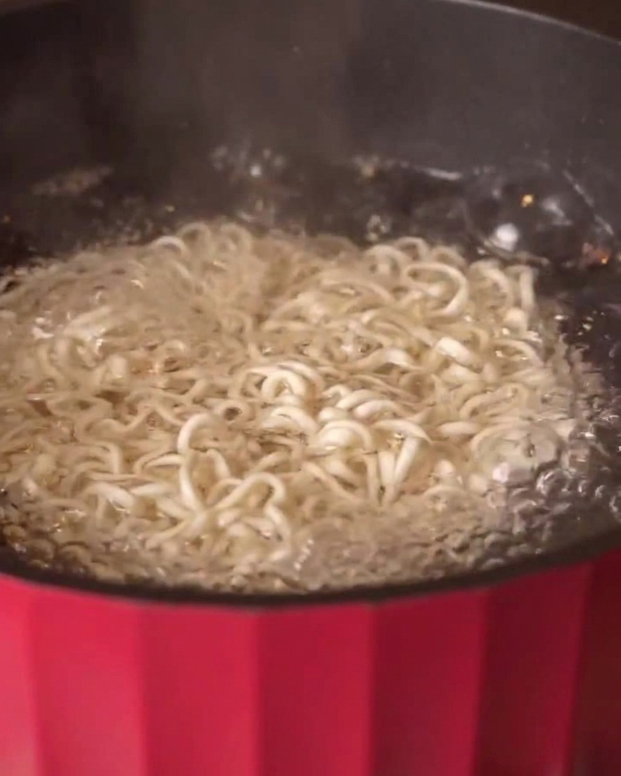 お湯の沸いた鍋の中で雑穀麺が茹でられている様子
