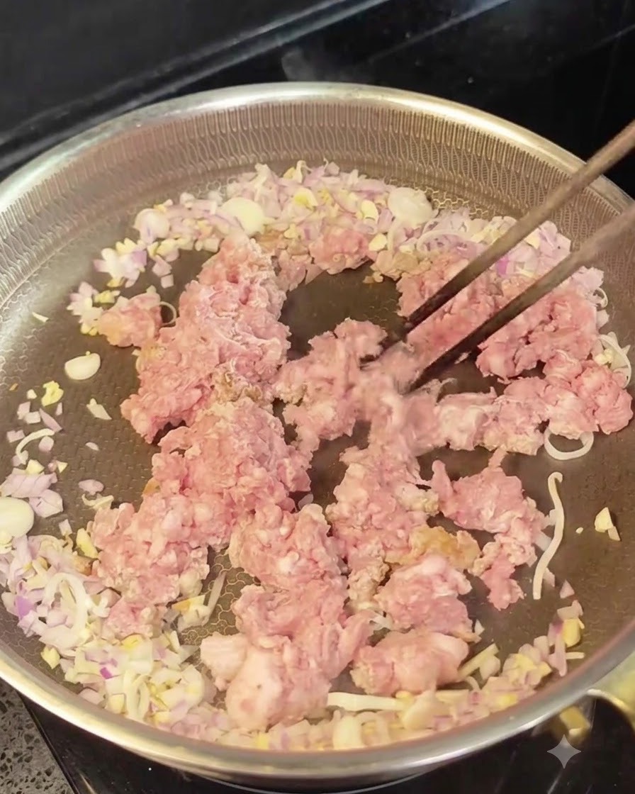 炒めた玉ねぎとにんにくの周りに生ひき肉を中央に置いている様子