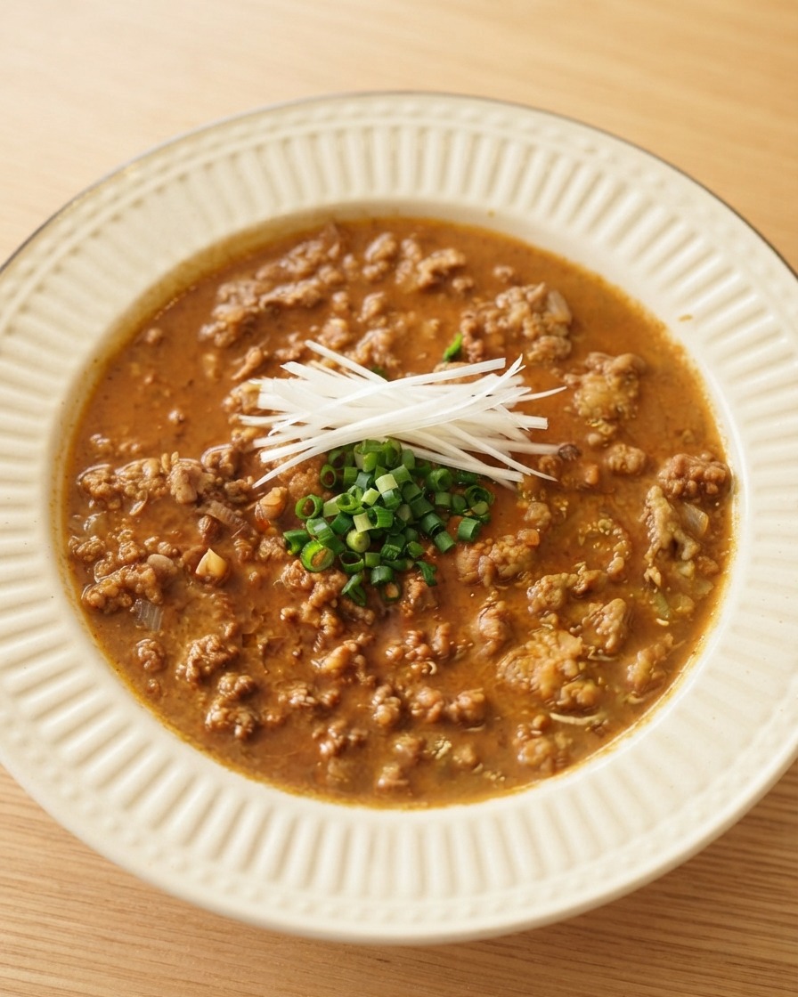 白いサービングボウルに入った濃厚な肉ダレの上に、白髪ねぎと刻み青ネギがきれいにトッピングされている様子