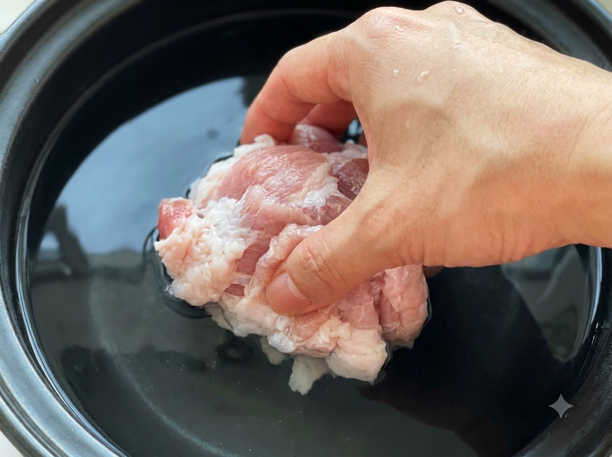 冷水と味噌を入れた鍋に、生の豚肉の塊を沈めている様子。