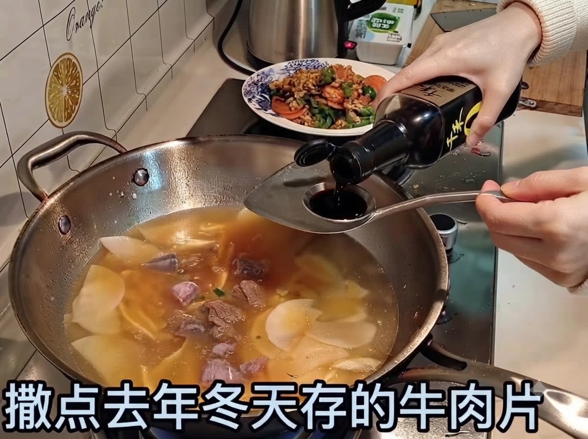 牛肉と野菜が入った煮込み中のスープに、醤油が注がれているところ。