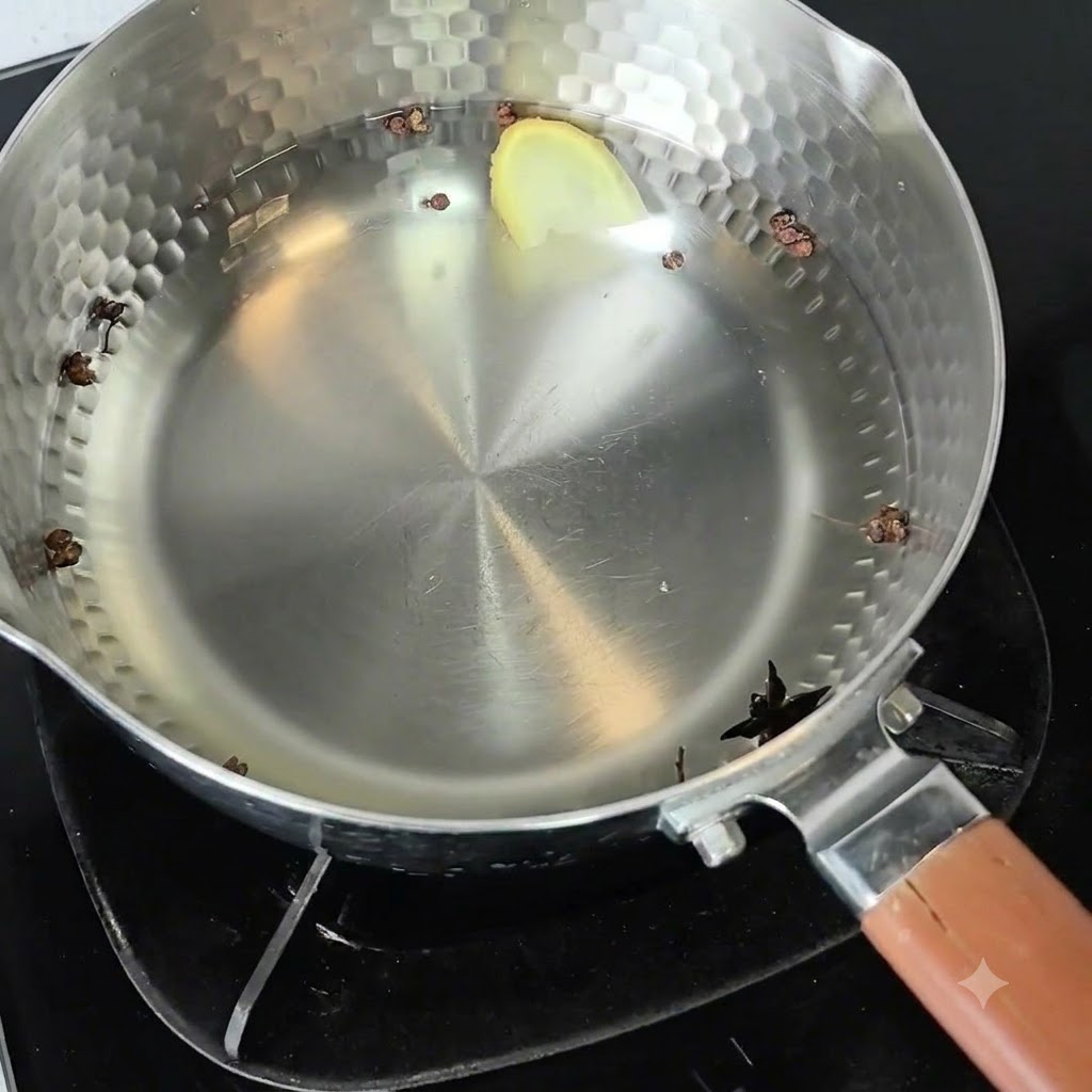 コンロに置かれた金属製の鍋。中には冷水、花椒、八角、スライスした生姜が入っている。