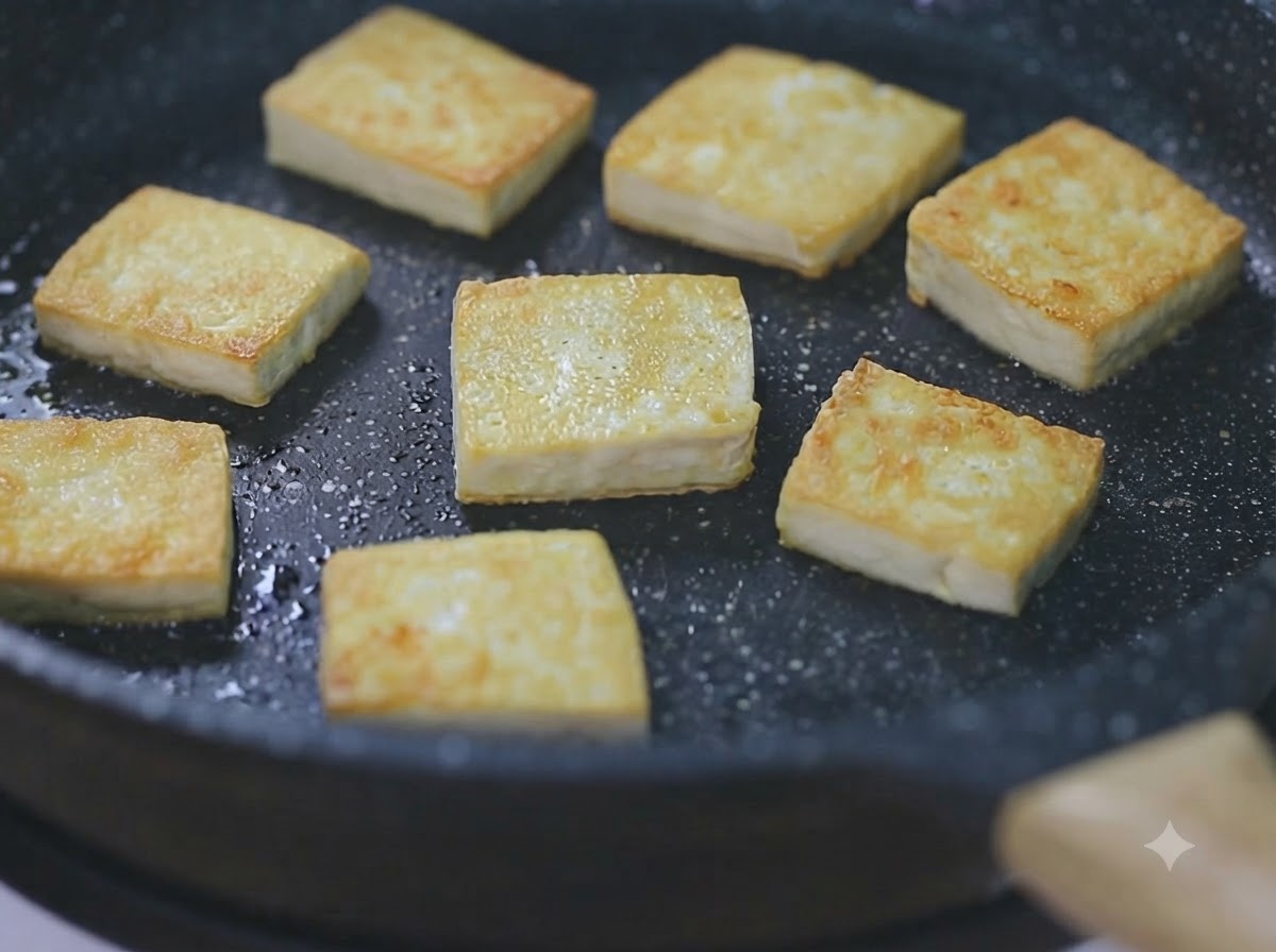 黒いフライパンの中で、弱火で焼かれたきつね色の豆腐の様子。
