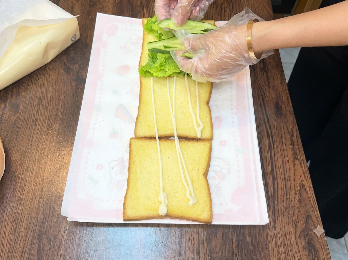 トーストの上のレタスに新鮮なきゅうりのスライスを並べている様子。