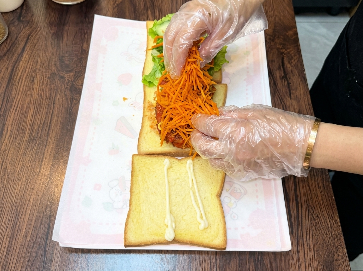 重ねたチキンカツの上に、鮮やかなオレンジ色の千切り炒め人参をこんもりと乗せている様子。