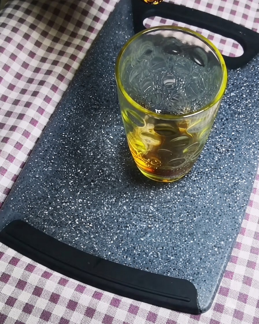 グレーのまな板の上の透明なガラス容器に濃口醤油が注がれている様子。