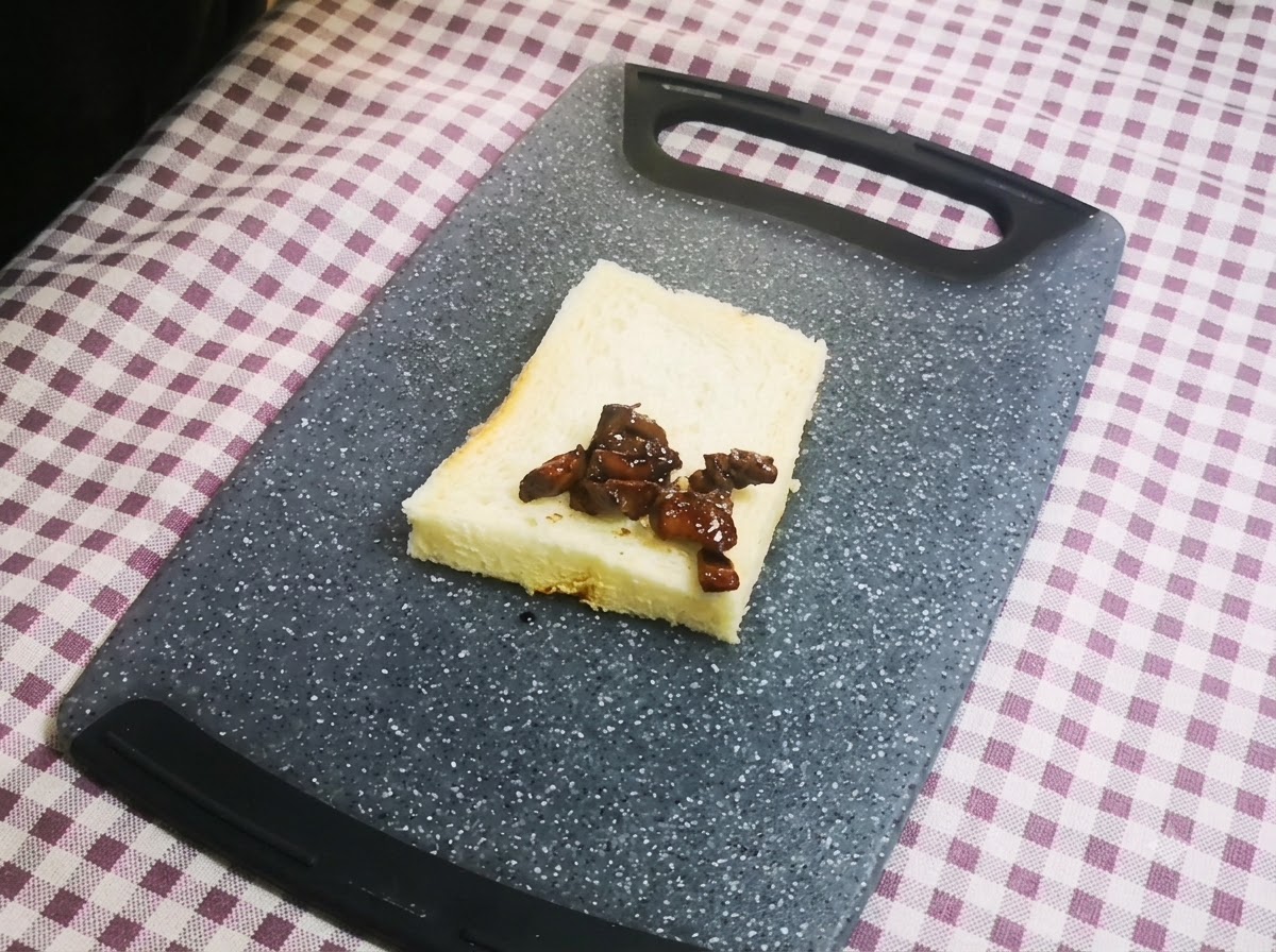 グレーのまな板の上に置いた1枚の食パンの中央に、濃い色の照り焼きチキンが綺麗にのせられているクローズアップ。