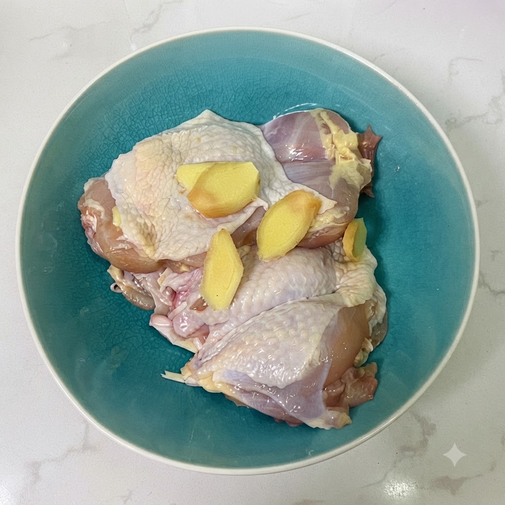 青いセラミックのボウルに入った、生姜スライスと醤油に浸かった鶏もも肉。