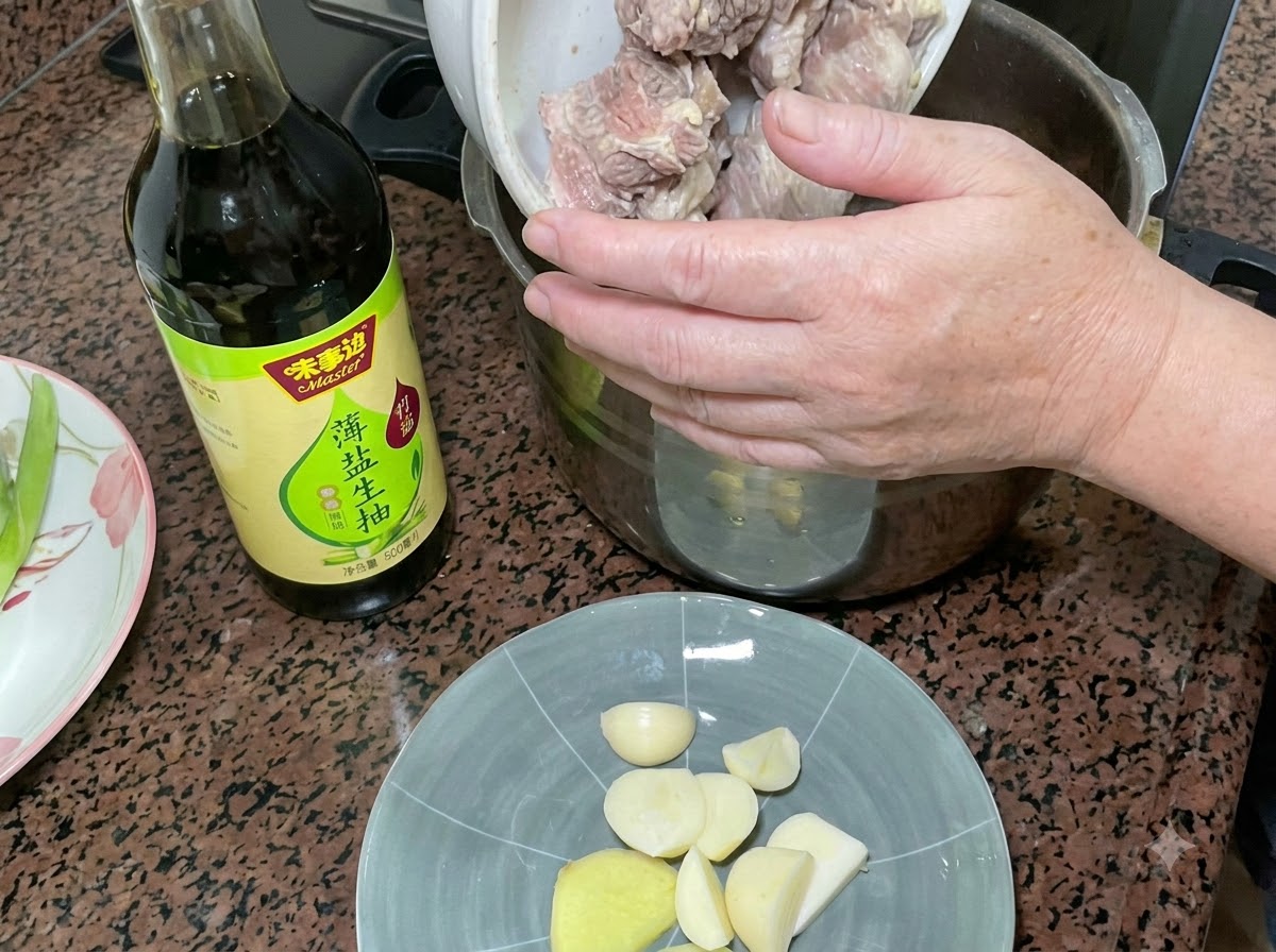 下茹でされた豚スペアリブを、薄口醤油のボトルやニンニク・生姜の皿の横にある圧力鍋に移している様子。