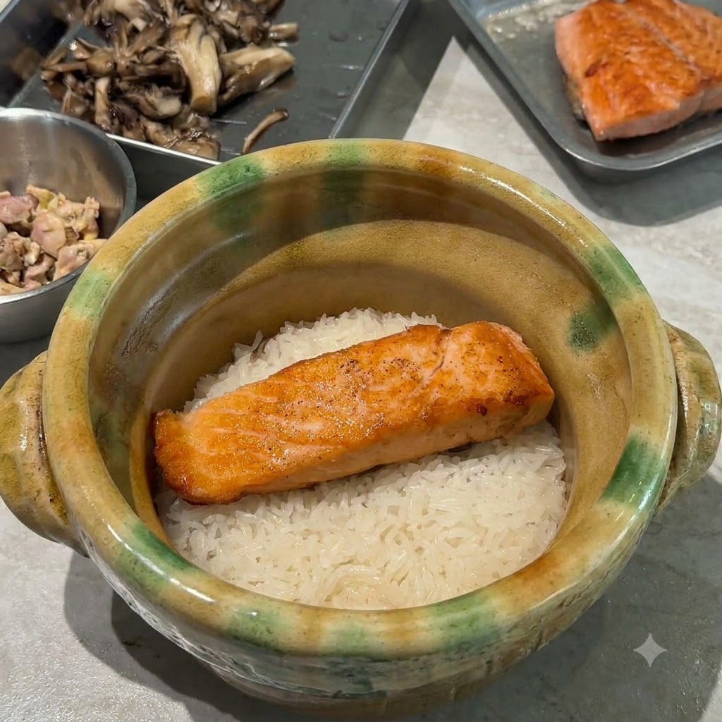 黄金色に炒めたマイタケを、土鍋の中のご飯とサーモンの上に美しく盛り付けている様子。