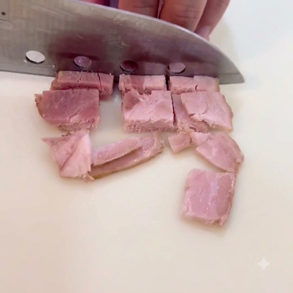 調理台の上でベーコンのスライスを小さな正方形のピースに刻んでいる様子。
