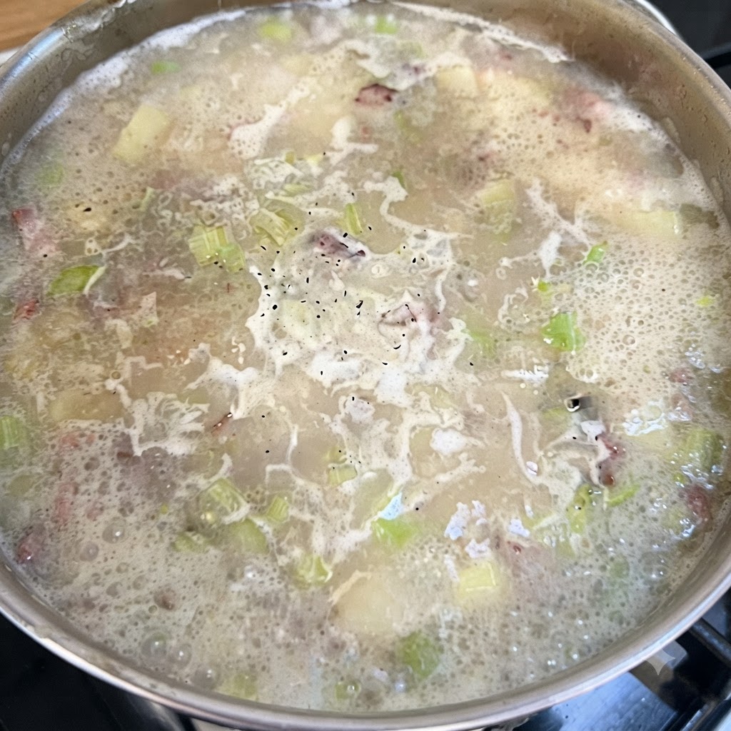 黒こしょうが泡立つ表面に散らされた、チャウダーのベースが弱火で煮込まれている鍋。