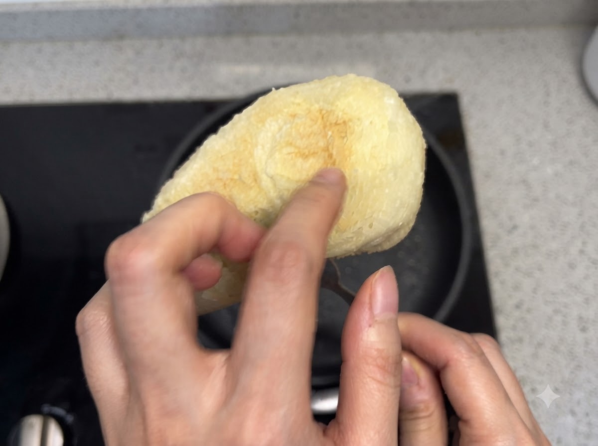 トーストしたパンの底面を手で押して焼き加減を確認している様子。