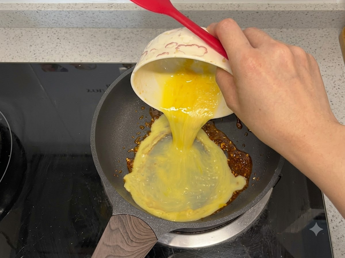 チリオイルの入ったフライパンに溶き卵が注がれている様子。