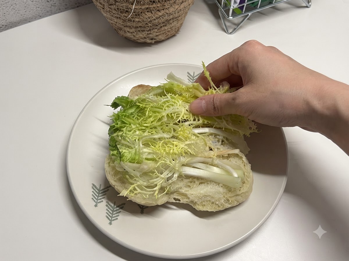 開いたチャバタパンの中に新鮮な千切りレタスが置かれている様子。