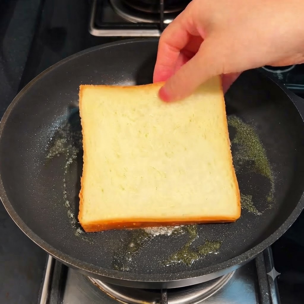 弱火のフライパンの上でバターと一緒にトーストされている食パンの薄切り。