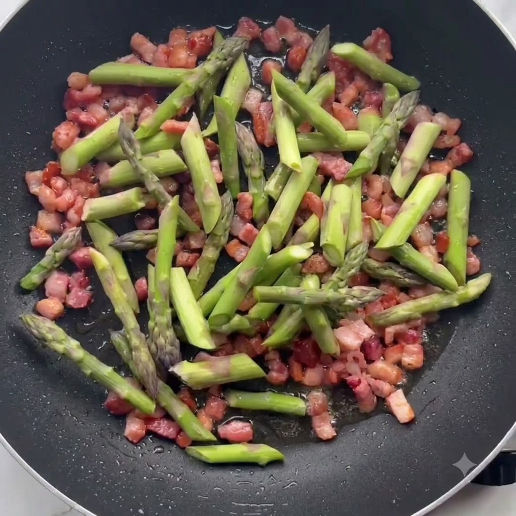 フライパンの中でカリカリのベーコンと一緒に緑色のアスパラガスが炒められている様子。