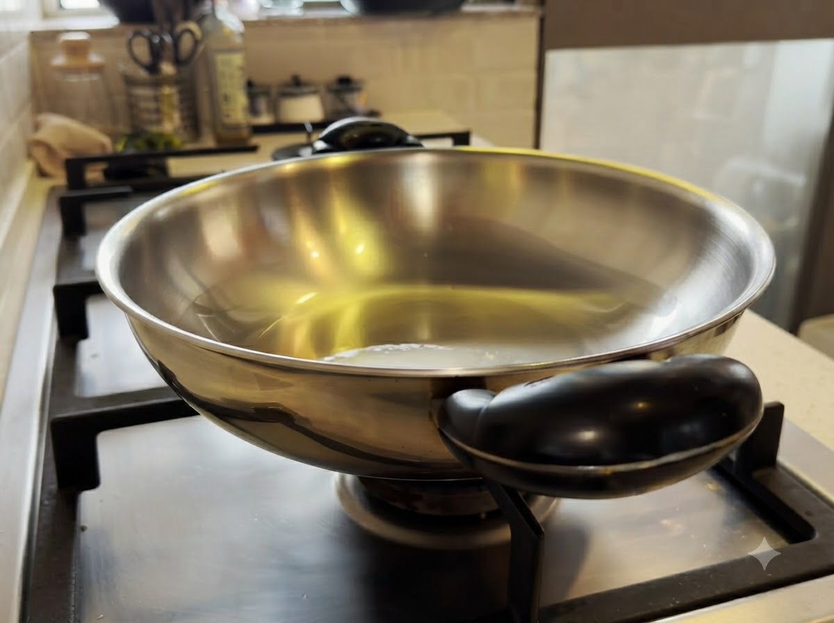 オリーブオイルを入れた熱した金属製の中華鍋で、鶏肉の小さなピースが炒められている様子。