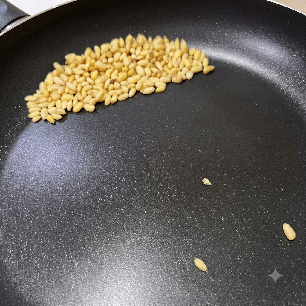 イタリアンペストパスタの準備として、油を敷いていないフライパンの中で松の実がきつね色に色づいている様子。