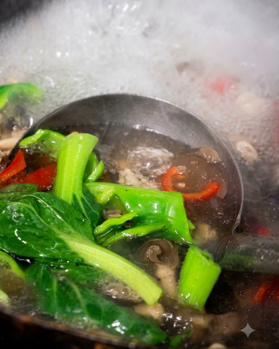 お玉で茹で上がったチンゲン菜、ピーマン、キノコをお湯からすくい上げている様子。