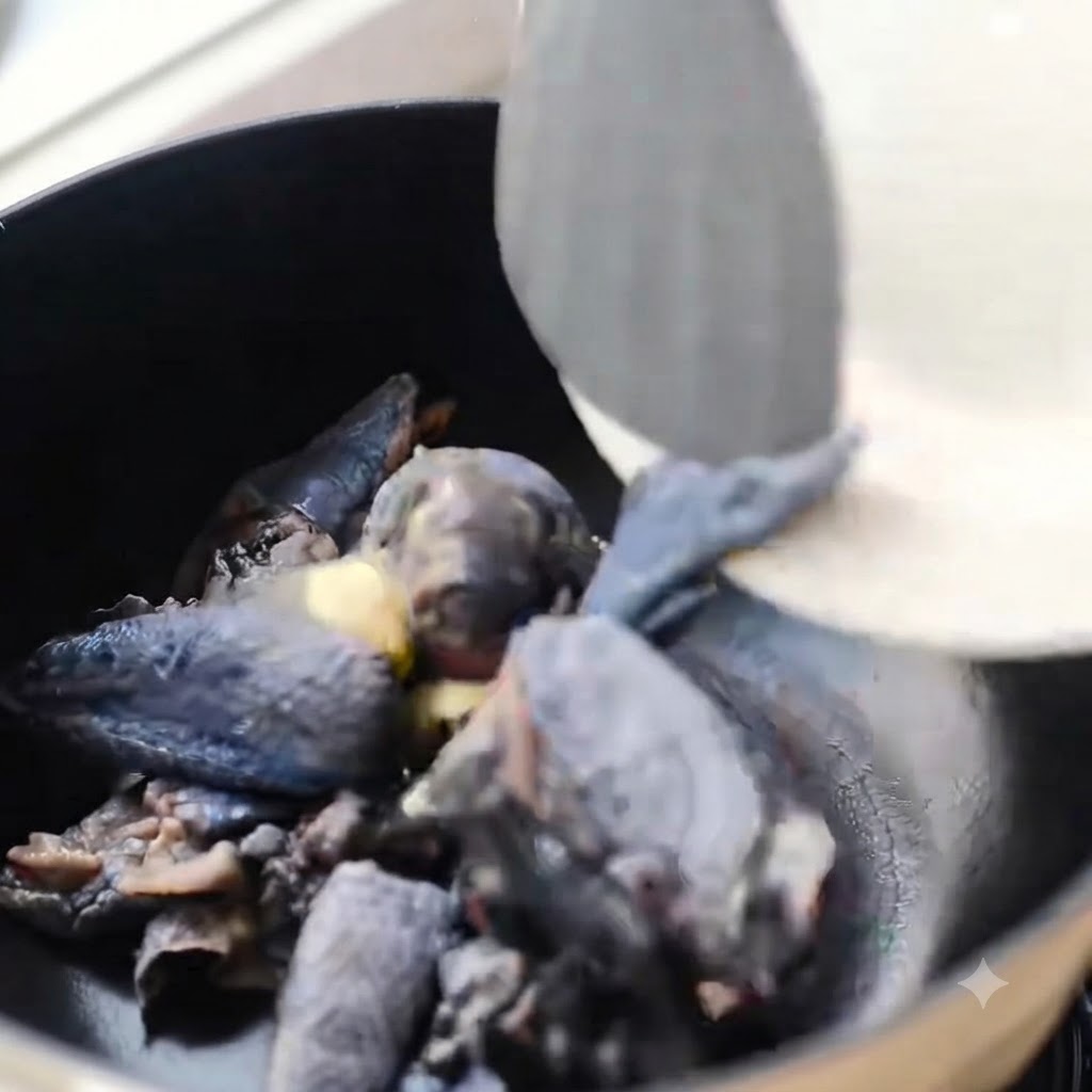 黒い鍋で生姜と一緒に炒められている黒皮鶏肉の切り身。