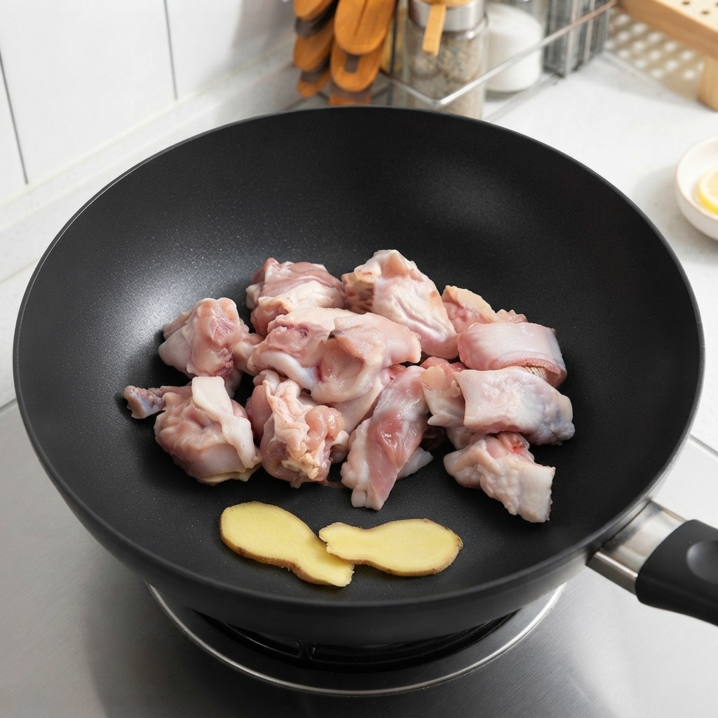 炒める前に中華鍋に並べられた生姜のスライスと生の鶏肉片。