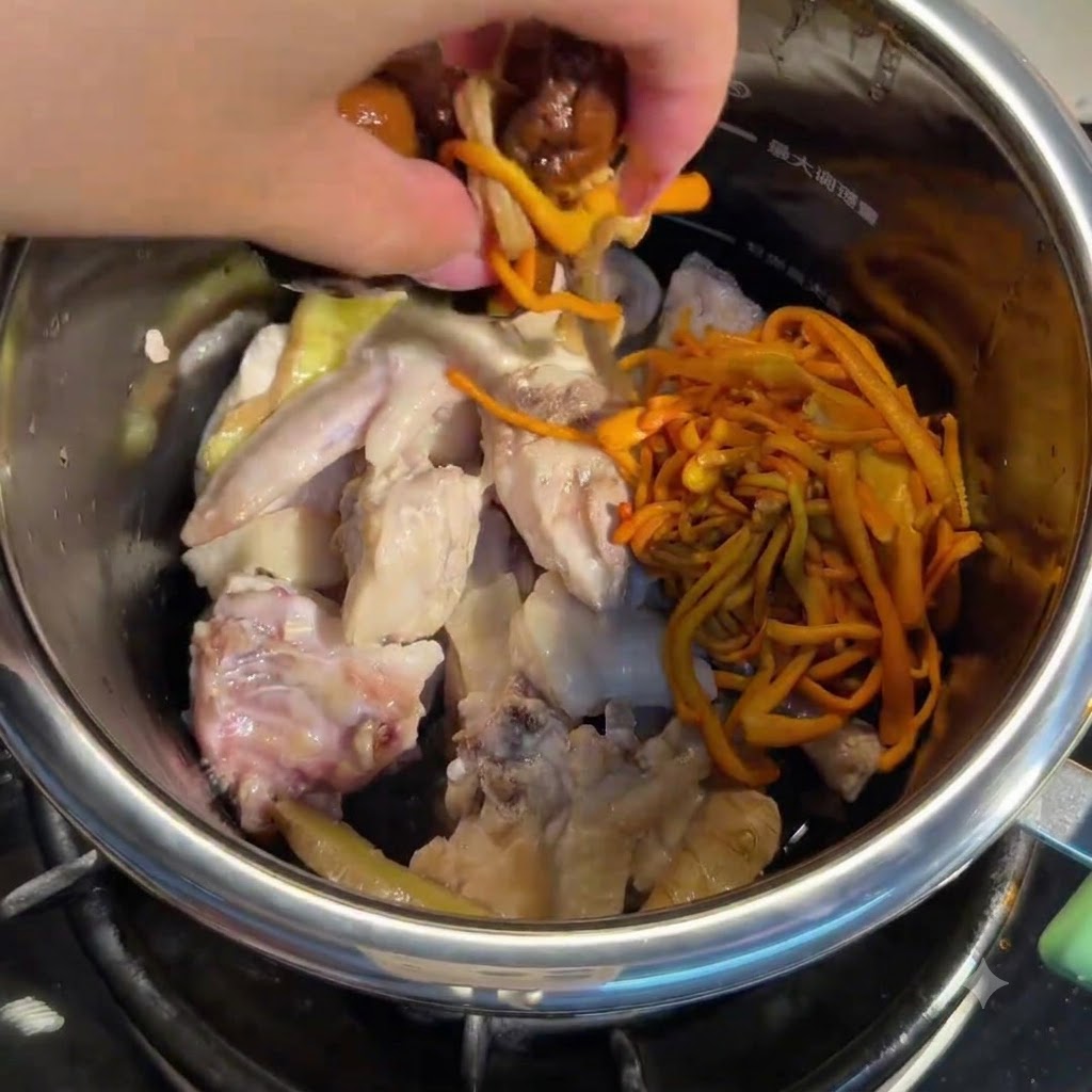 鶏肉の入った鍋に戻したきのこと冬虫夏草を加える手。