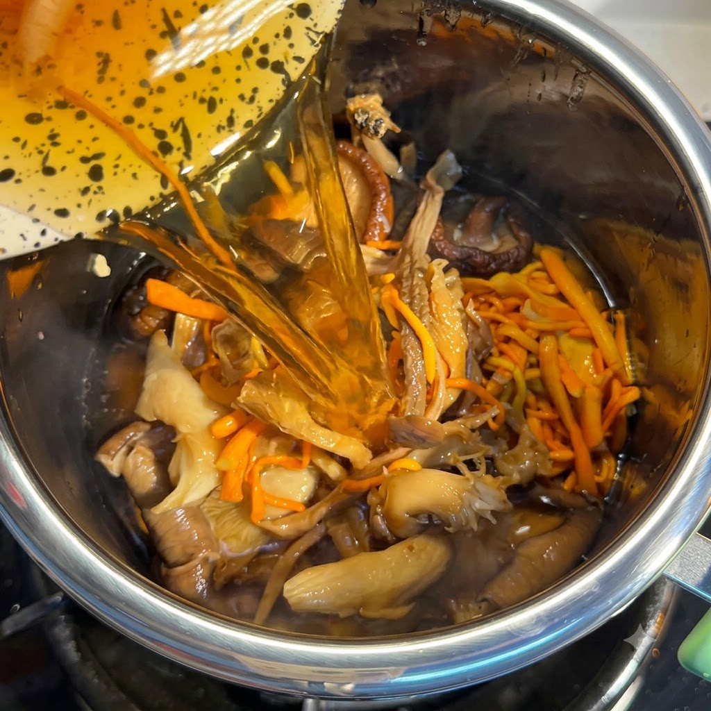 材料の入った鍋に注がれるきのこの戻し汁。
