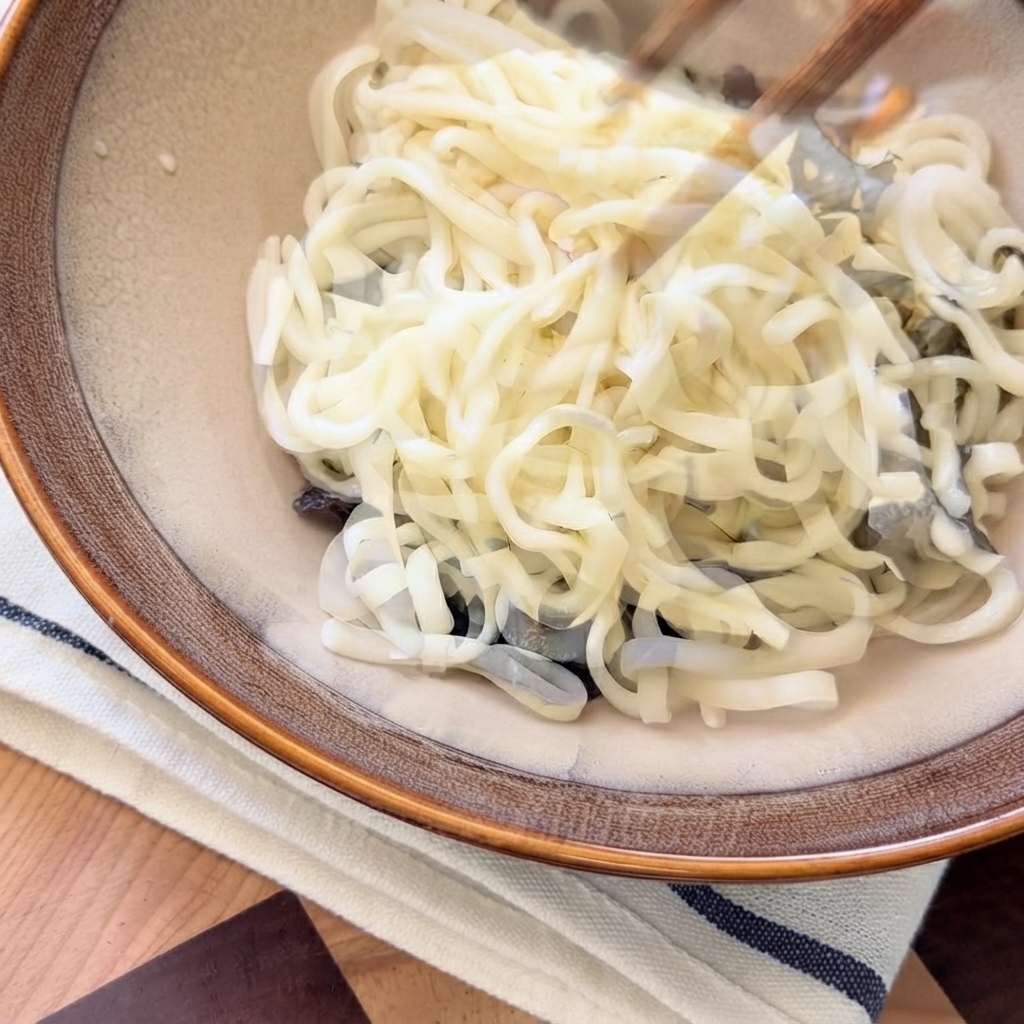 サービングボウルの中の麺の上から、熱いキノコ出汁が上空から注がれている様子